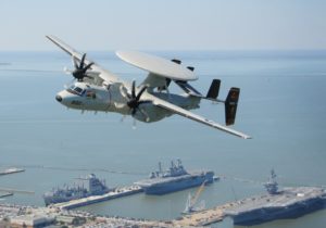 A E-2C/D Hawkeye navy plane flying above a port