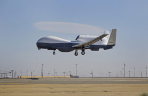 A MQ-4C Triton uncrewed navy drone flying above the ground